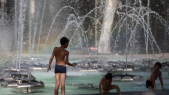 Des enfants jouent dans une fontaine publique pour se rafraîchir dans la ville de Perpignan, dans le sud de la France, le 17 juin 2022.